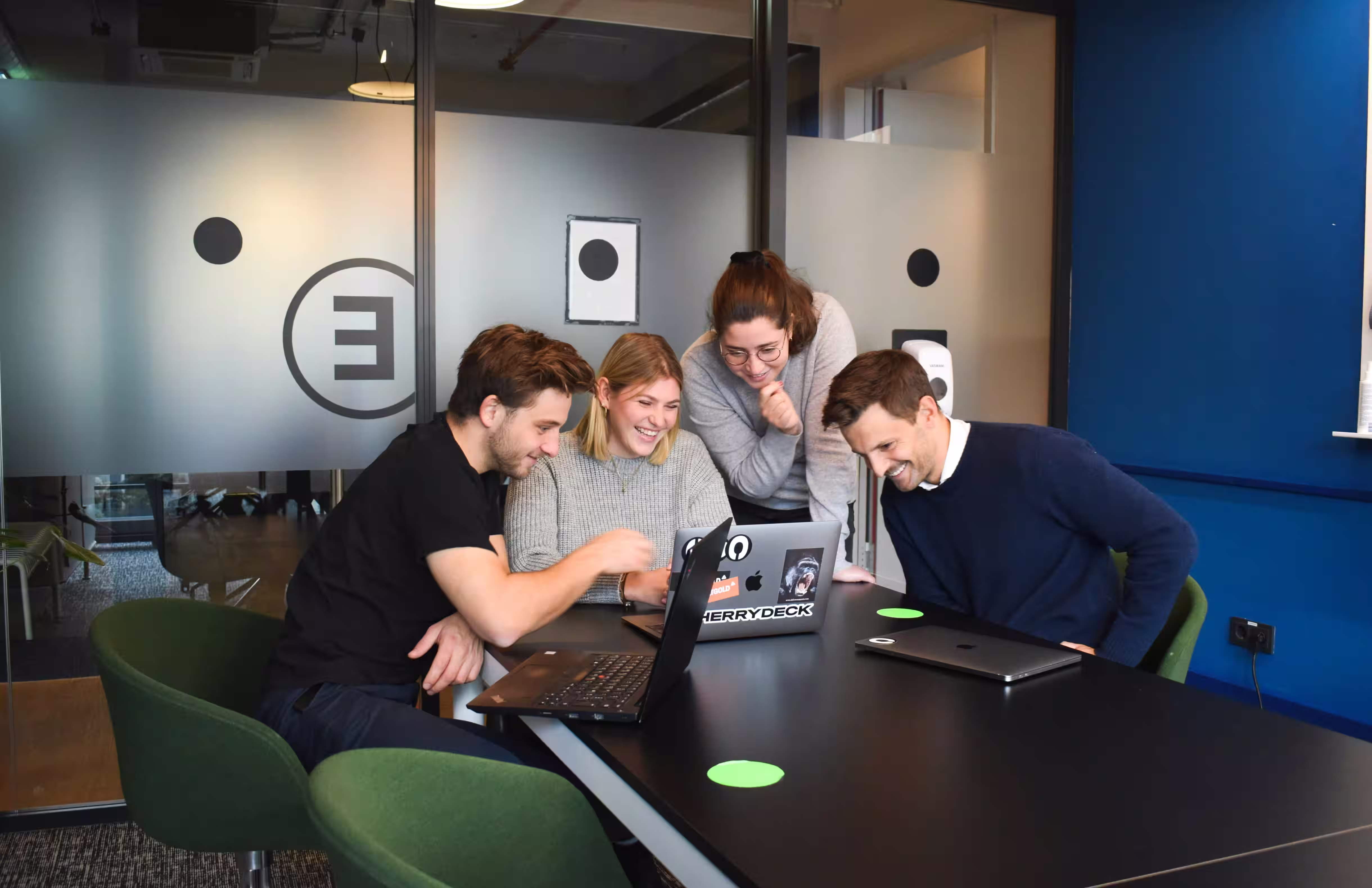 A small team collaborating around a laptop in a modern office